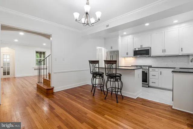 a kitchen with stainless steel appliances granite countertop a dining table chairs microwave and cabinets