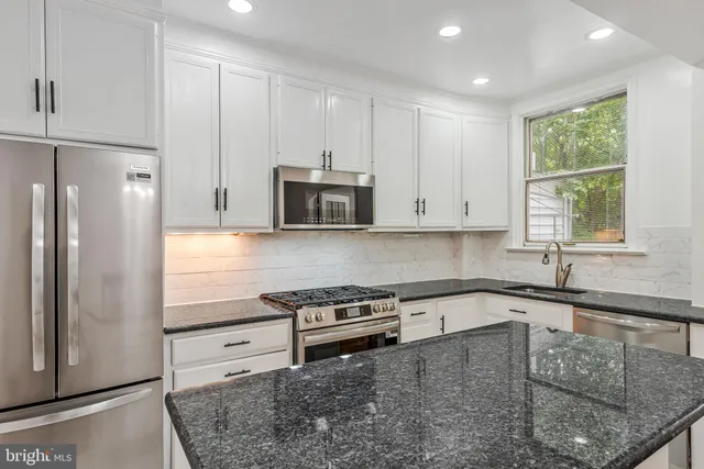 a kitchen with stainless steel appliances granite countertop a refrigerator and a sink