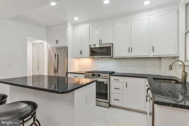 a kitchen with stainless steel appliances granite countertop a sink a stove and a refrigerator