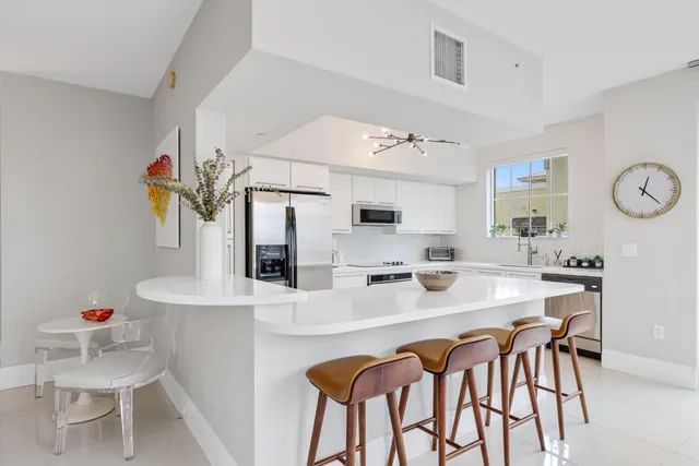 a large white kitchen with stainless steel appliances lots of white furniture