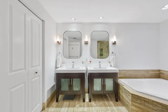 a spacious bathroom with a double vanity sink mirror and bathtub