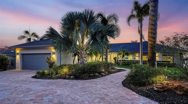 a front view of a house with a yard and palm trees