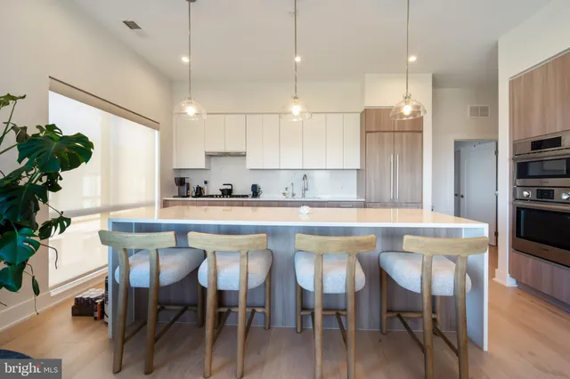 a kitchen with kitchen island granite countertop a table chairs sink and cabinets