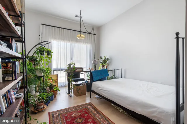 a bedroom with a bed a potted plant and a book shelf
