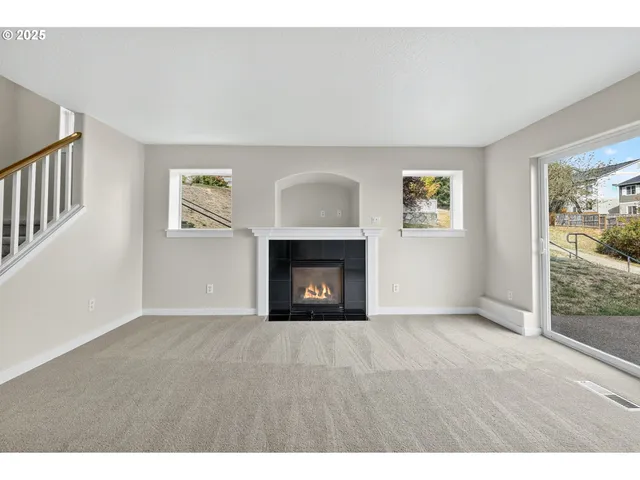 a view of an empty room with a window and fireplace