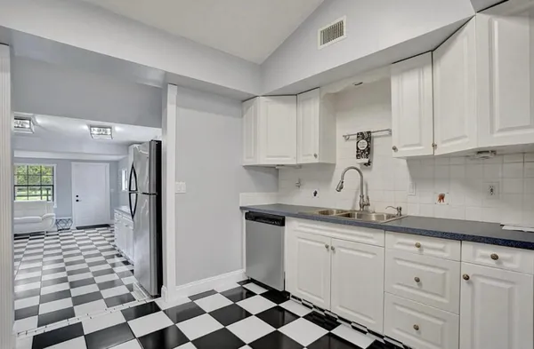 a kitchen with a sink a refrigerator and cabinets
