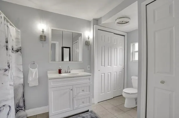 a bathroom with a toilet a sink a mirror a lamp and vanity