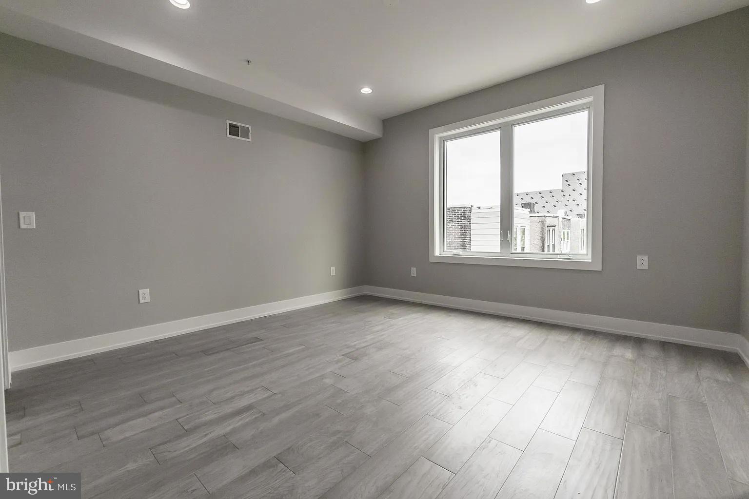 2055 Tasker Street Philadelphia, PA 19145 - Photo 15 of 40 a view of an empty room with wooden floor and a window