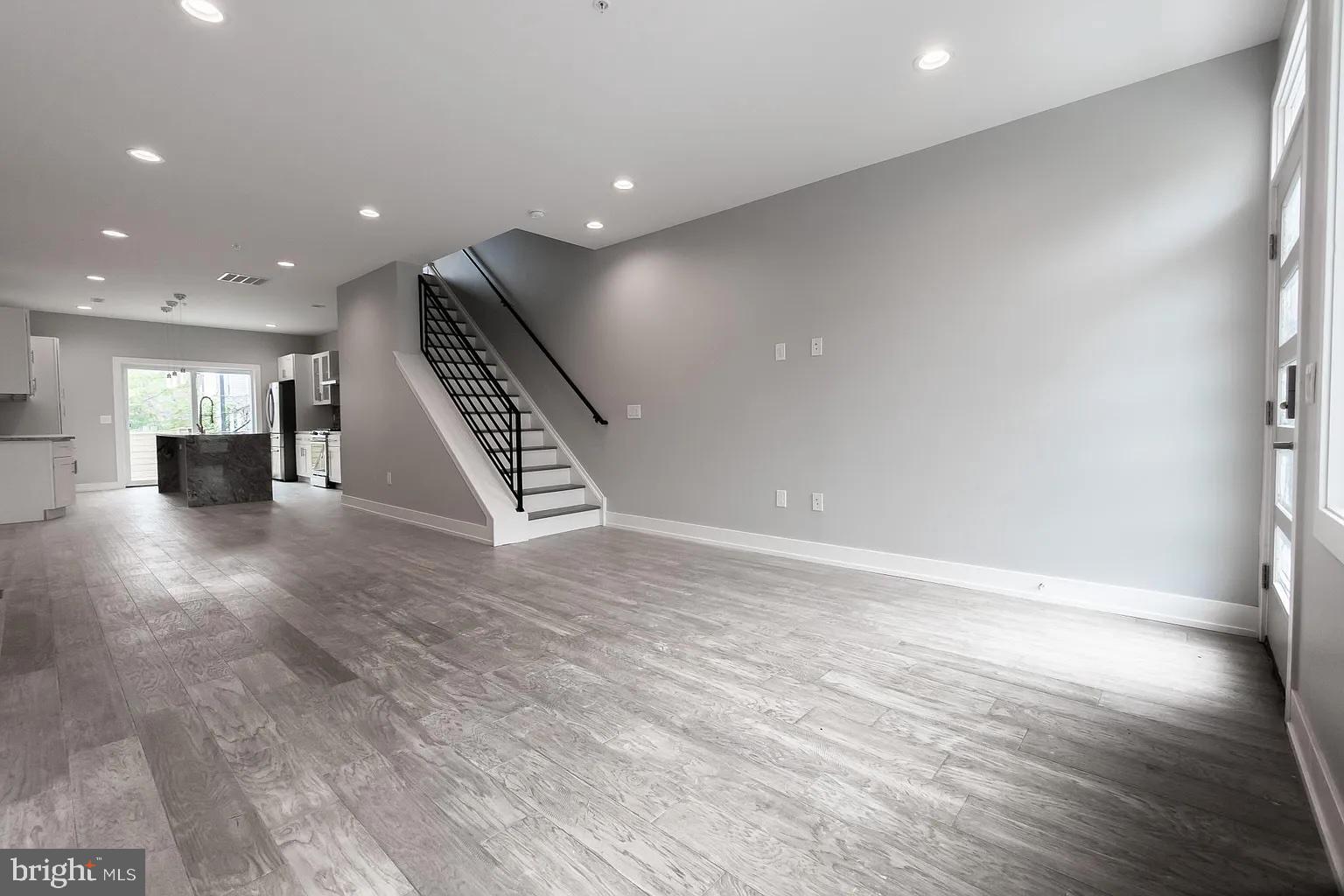 2055 Tasker Street Philadelphia, PA 19145 - Photo 3 of 40 an empty room with wooden floor staircase and kitchen view