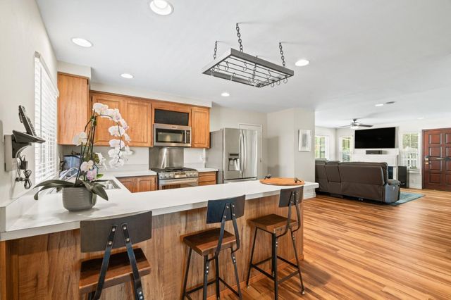 a kitchen with stainless steel appliances a stove a sink a microwave a refrigerator cabinets and dining table