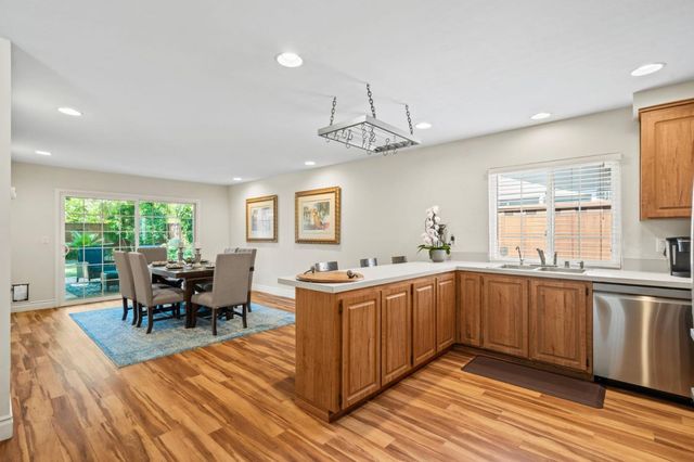 a kitchen with stainless steel appliances granite countertop a stove top oven a dining table and chairs with wooden floor