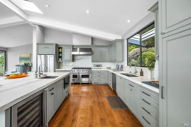 a large kitchen with stainless steel appliances lots of counter top space a sink a stove and a window