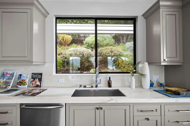 a kitchen with white cabinets and a window