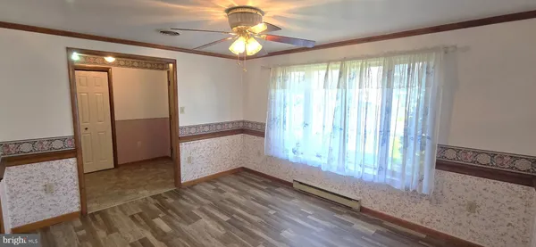 an empty room with wooden floor fan and windows