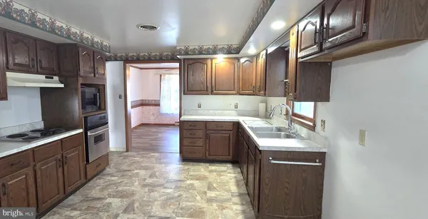 a kitchen with kitchen island granite countertop a sink stove and cabinets