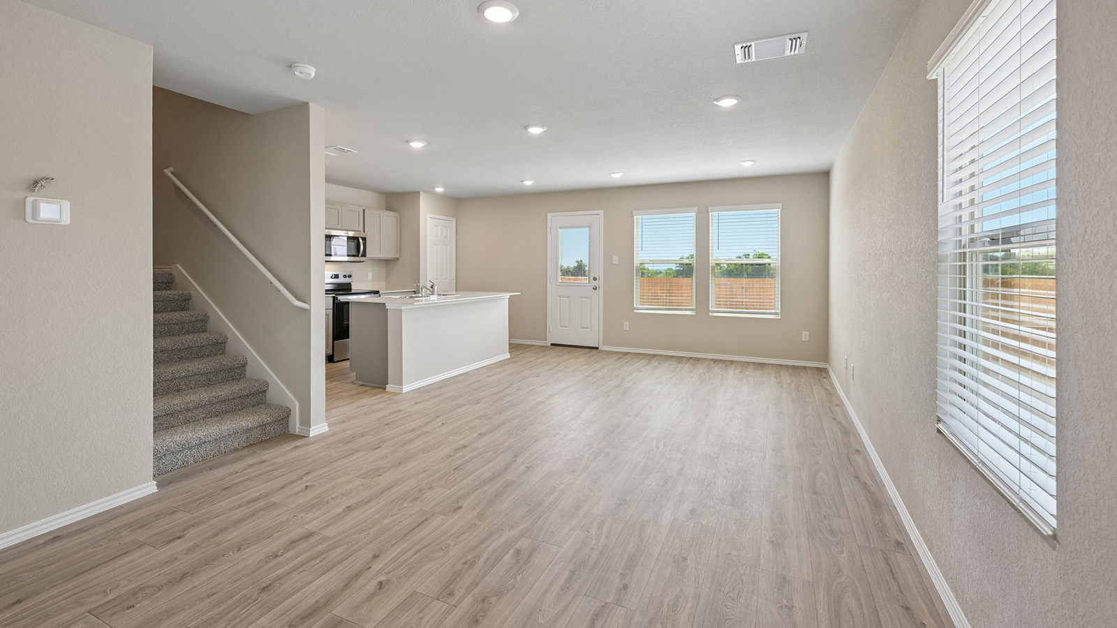 Smooth wood-style flooring runs through this airy, open-concept living space with recessed lighting.