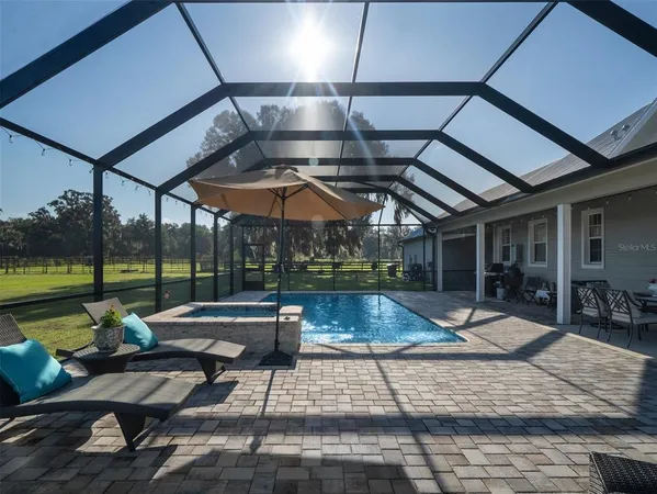 a view of pool with table and chairs under an umbrella