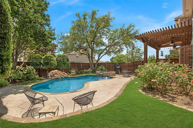 a view of a backyard with table and chairs potted plants and large tree