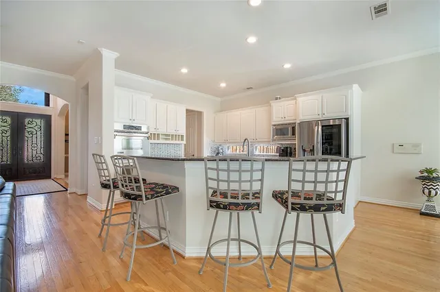 a kitchen with stainless steel appliances kitchen island granite countertop wooden floor and white cabinets