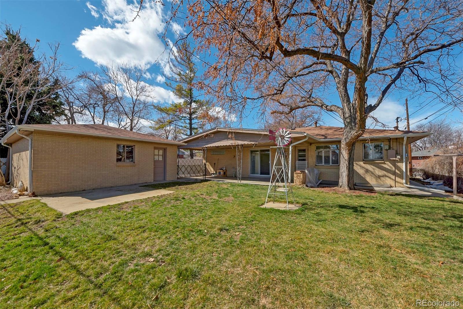 3880 Allison Street Wheat Ridge, CO 80033 - Photo 18 of 18 a backyard of a house with large trees and table and chairs under an umbrella