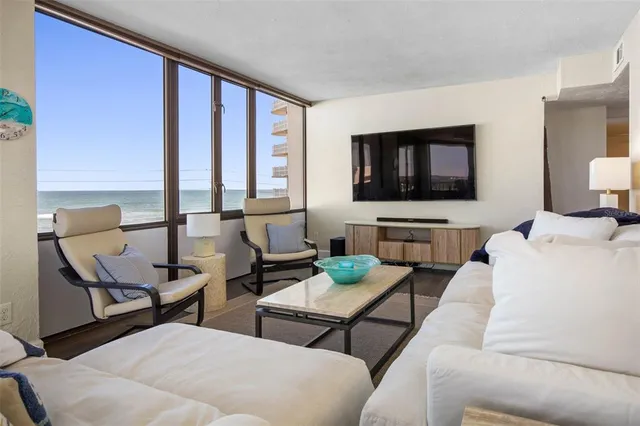 a living room with furniture a large window and wooden floor