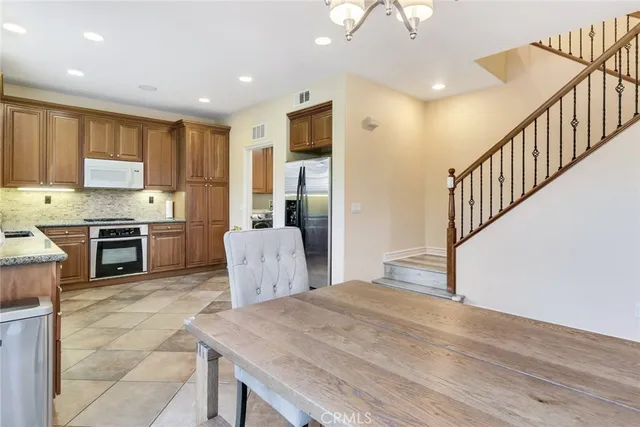 a kitchen with kitchen island a stove a refrigerator a sink a dining table and chairs with wooden floor