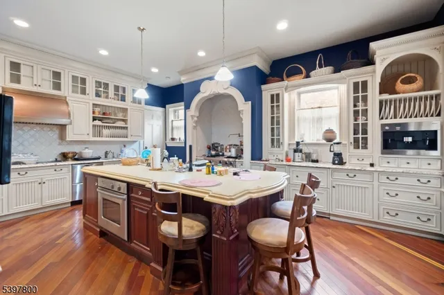 a kitchen with stainless steel appliances granite countertop a stove a sink dishwasher a dining table and chairs with wooden floor