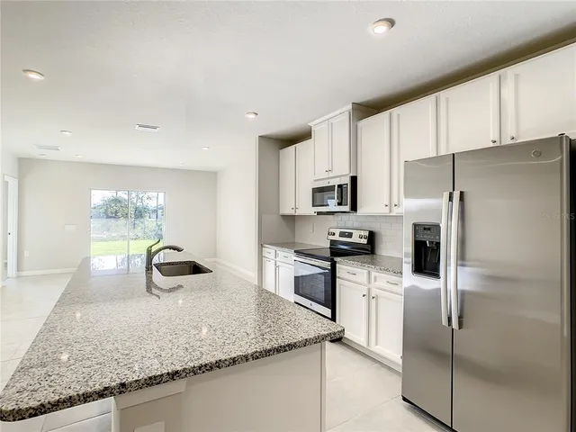 a kitchen with stainless steel appliances granite countertop a sink a stove and a refrigerator