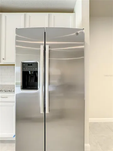 a close view of a refrigerator in kitchen and empty room