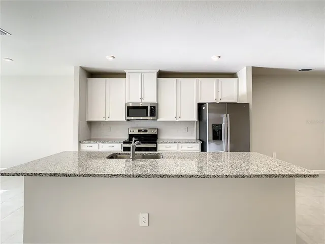 a kitchen with stainless steel appliances granite countertop a sink refrigerator stove microwave and cabinets