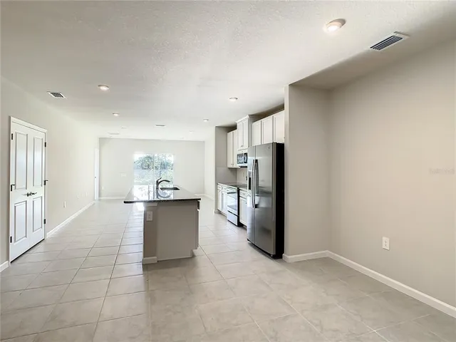 a large white kitchen with a refrigerator and a sink