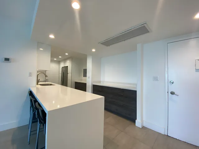 a large white kitchen with a sink a refrigerator and a sink