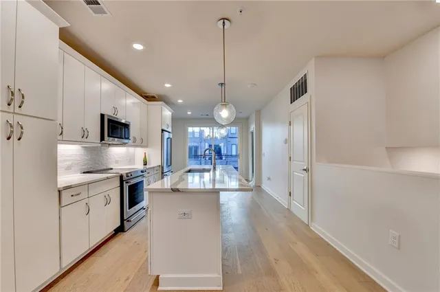 a large kitchen with stainless steel appliances kitchen island granite countertop a stove a sink and a refrigerator