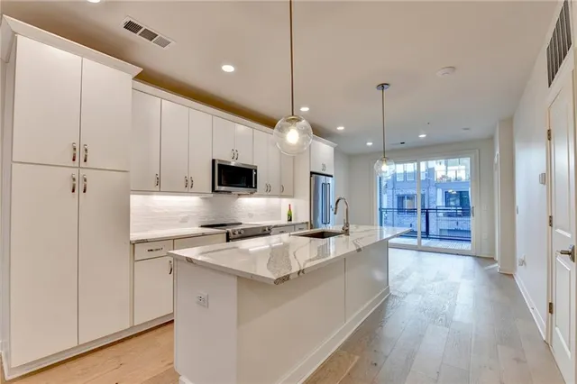 a kitchen with stainless steel appliances granite countertop a sink a stove and a wooden floors