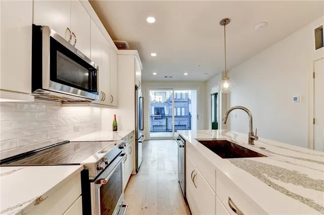 a kitchen with stainless steel appliances granite countertop a sink a stove and a wooden floors