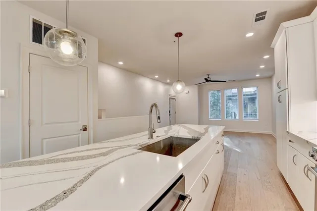 a kitchen with stainless steel appliances granite countertop a sink a stove a refrigerator and island with wooden floor