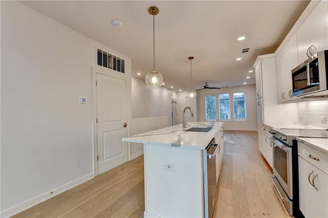 a kitchen with stainless steel appliances granite countertop a sink a stove and a wooden floors