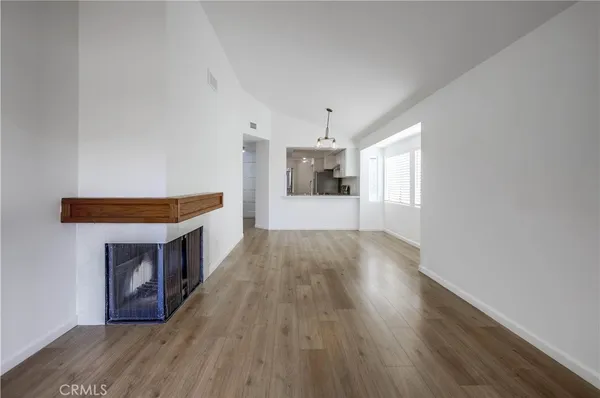 a big room with wooden floor and a kitchen