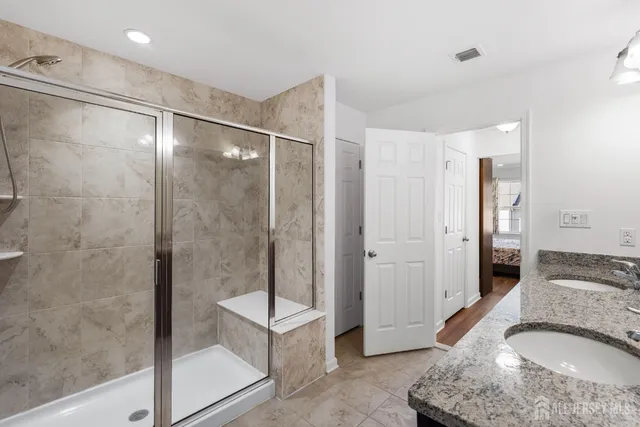 a bathroom with a granite countertop shower a sink and a mirror