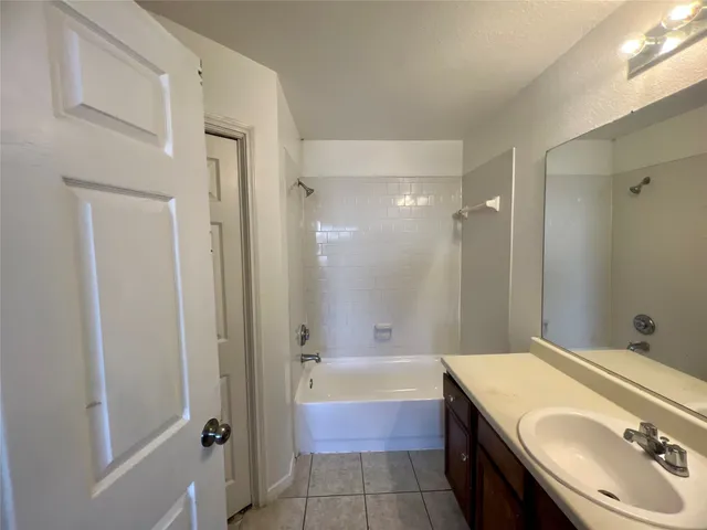 a bathroom with a tub sink vanity granite and shower