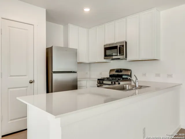 a kitchen with stainless steel appliances a refrigerator sink and microwave