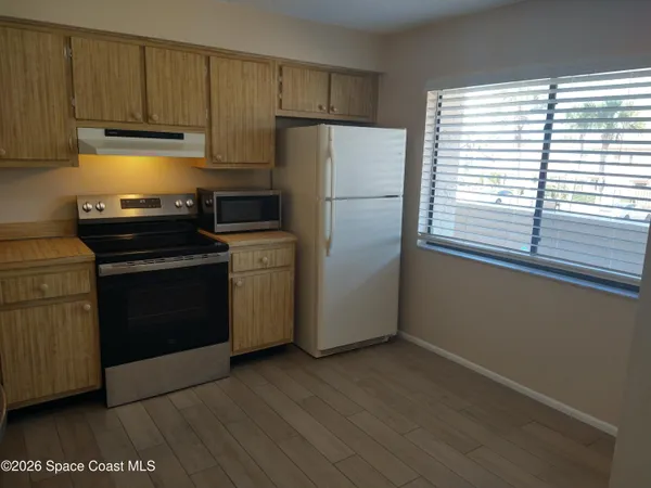 a kitchen with a refrigerator stove and wooden cabinets