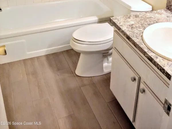 a bathroom with a granite countertop sink and a toilet