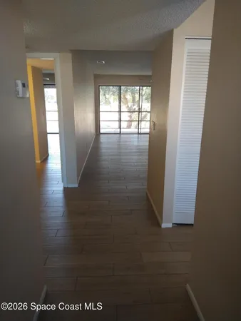 a view of hallway with window and wooden floor