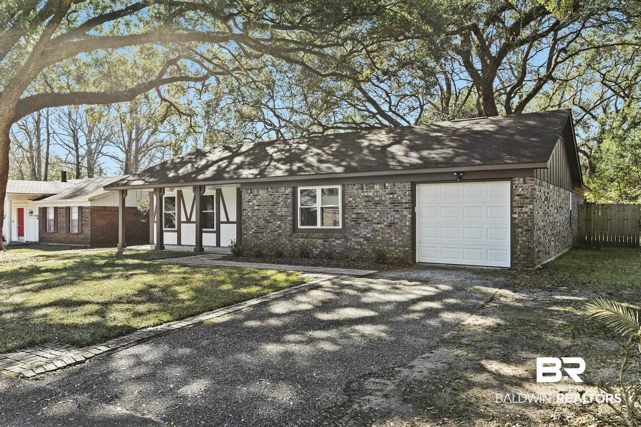 5817 Woodgate Road Mobile, AL 36609 - Photo 4 of 85 View of front of house with a front lawn, brick siding, fence, and an attached garage