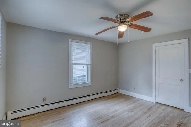 an empty room with wooden floor fan and windows