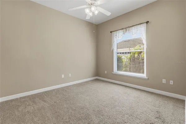 a view of an empty room with window and a kitchen