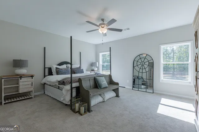 a spacious bedroom with a bed a chandelier and window