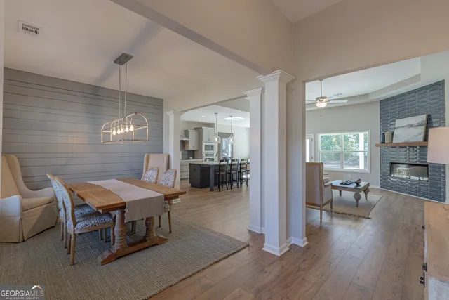 a dining room with wooden floor a chandelier a wooden table and chairs