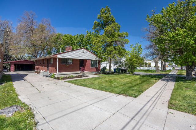667 North 100 East Logan, UT 84321 - Photo 5 of 41 View of front of home featuring covered porch, a front lawn, a chimney, brick siding, and an outbuilding